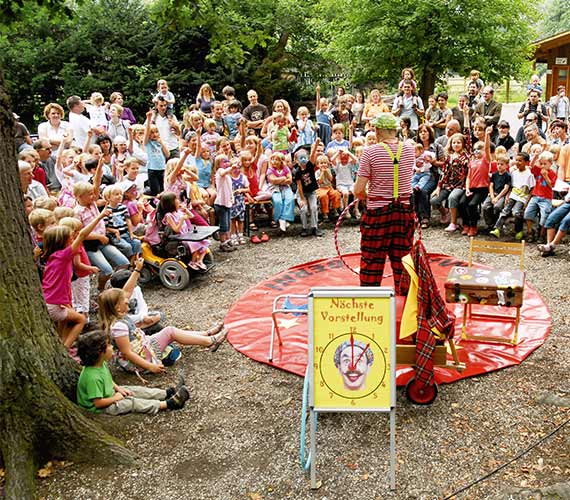 Große Gruppe an Kindern sitzen um Clown herum | Wisentgehege Springe